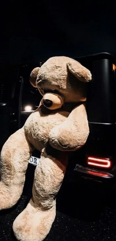 Giant teddy bear leaning out of a car at night.