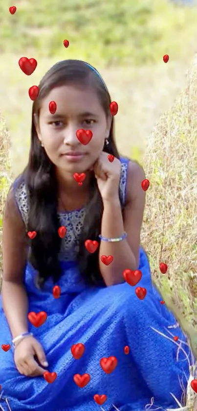 Girl in a blue dress with hearts in a natural field setting.