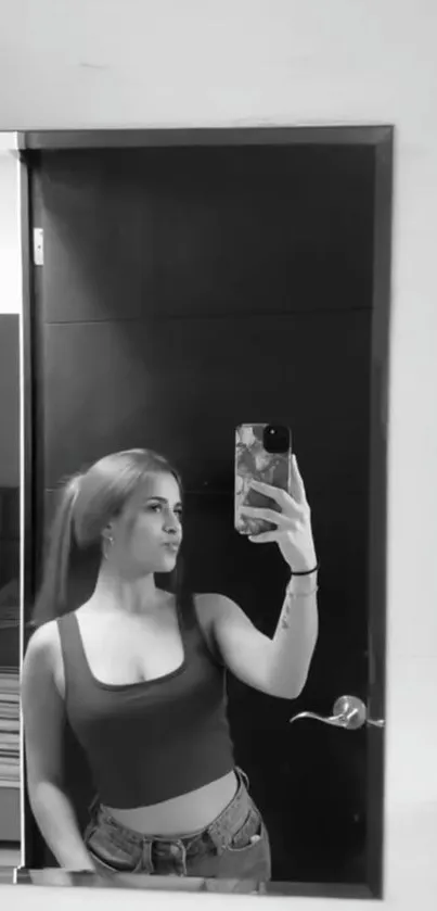 Black and white girl taking mirror selfie in room.