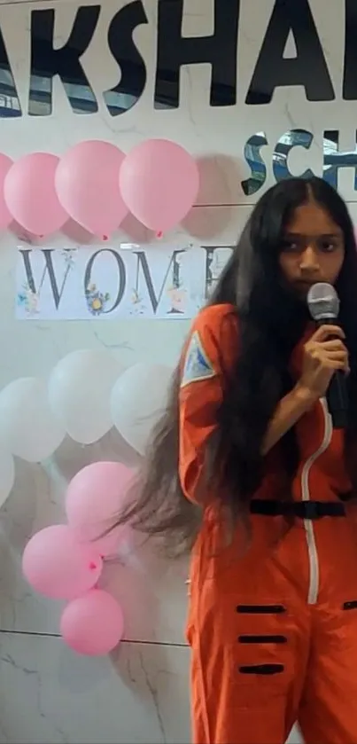 Girl in orange spacesuit with balloons backdrop.