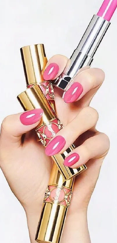 Hand holding pink lipstick with gold accents on a white background.