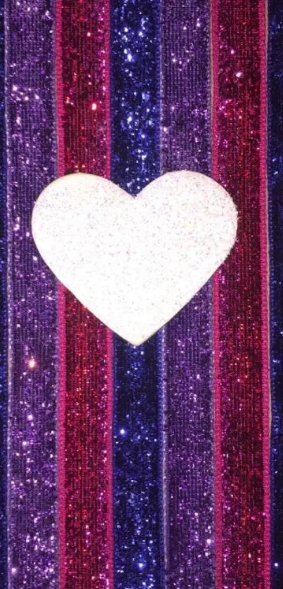 White glitter heart on purple, blue, and pink striped background.