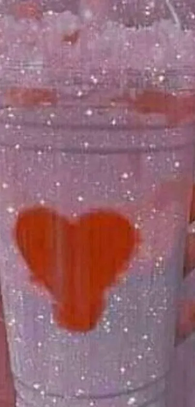 Glittery milkshake with orange heart design on pink background.