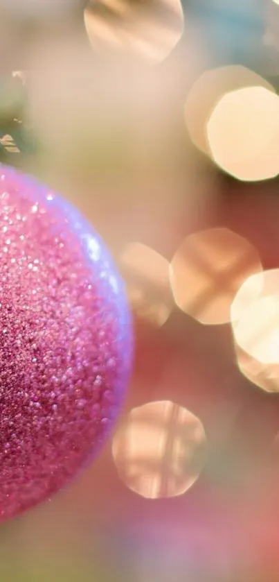 Pink glittery Christmas ornament with bokeh background.