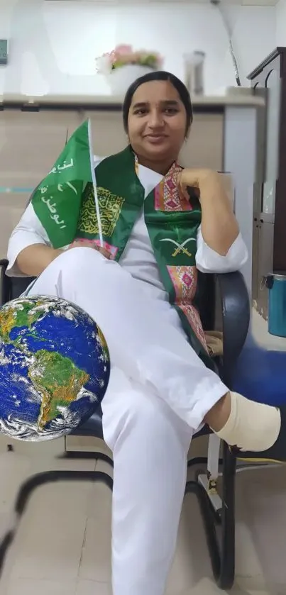 Person in traditional attire with a globe and green flag in a modern office setting.