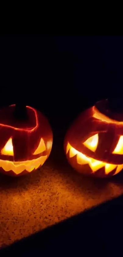 Two carved pumpkins glowing in the dark.