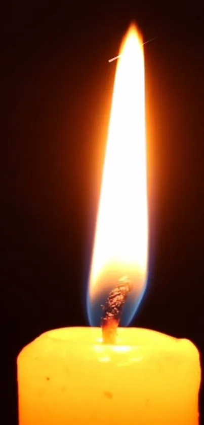 A glowing candle flame against a dark background for a mobile wallpaper.