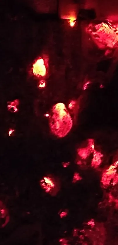 Glowing red embers on a dark background, emitting warm light.