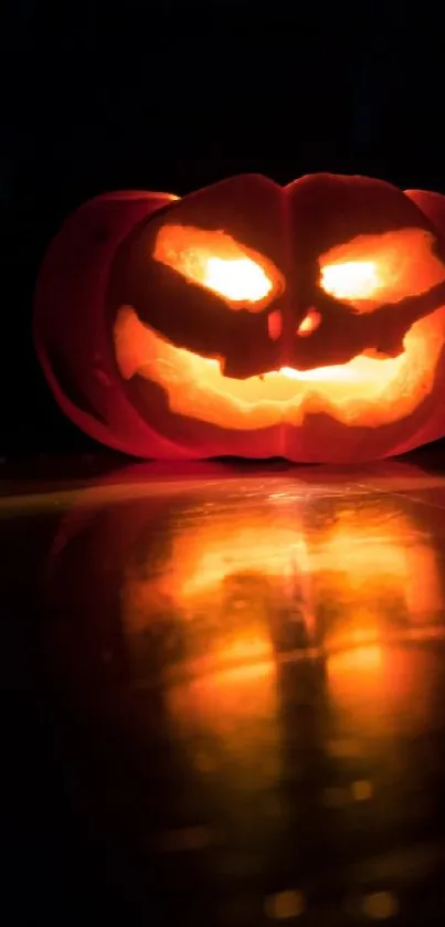 Glowing carved pumpkin with orange reflection, perfect for Halloween wallpaper.