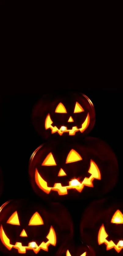 Glowing Halloween pumpkins stacked on a dark background.