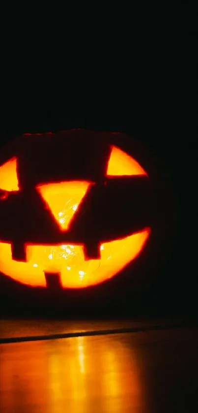 Halloween jack-o'-lantern with an orange glow against a dark background.