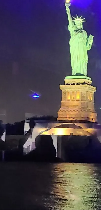 Nighttime view of illuminated Statue of Liberty with reflections on the water.