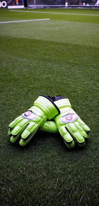 Green goalkeeper gloves resting on football field.