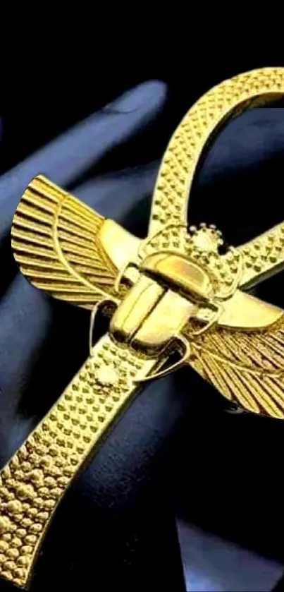 Golden ankh with wings on a dark background, symbolizing Egyptian heritage.