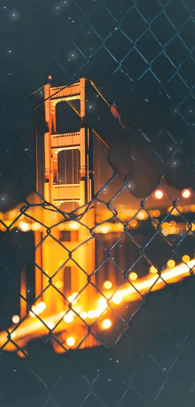 Golden illuminated bridge viewed through a wire fence at night.