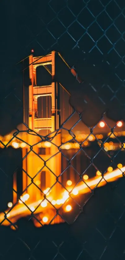 Golden Gate Bridge at night, viewed through a fence with city lights.