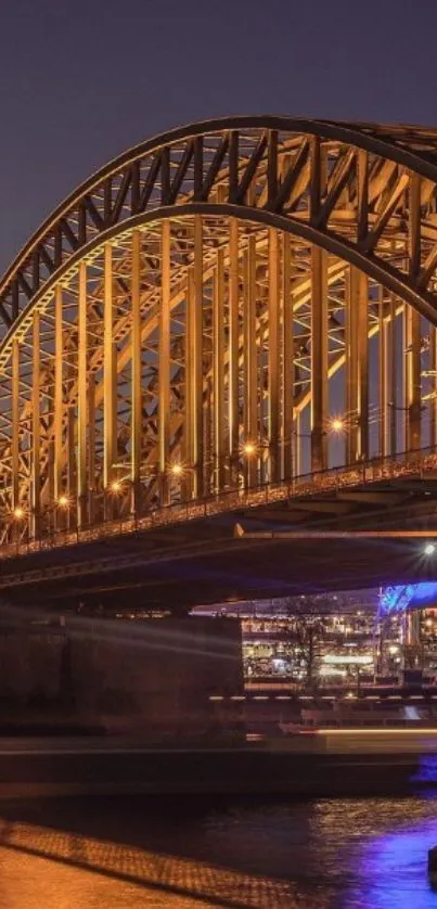 Golden bridge illuminated at night over a calm river.