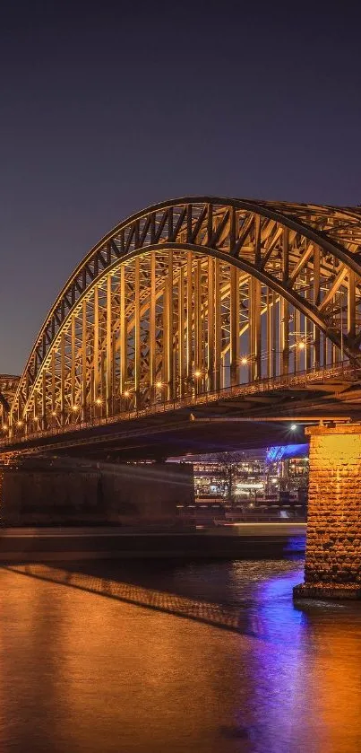 Golden bridge illuminated at night with reflections on water.