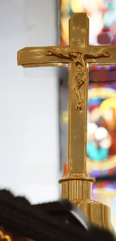Golden crucifix with stained glass background in church setting.