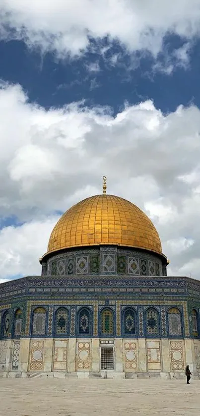 Golden dome under cloudy blue sky with intricate architecture.