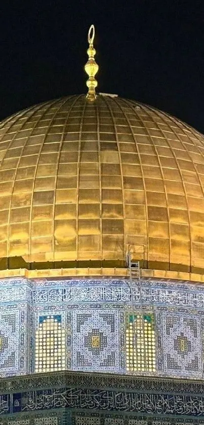 Golden dome of a mosque with intricate blue tile details at night.