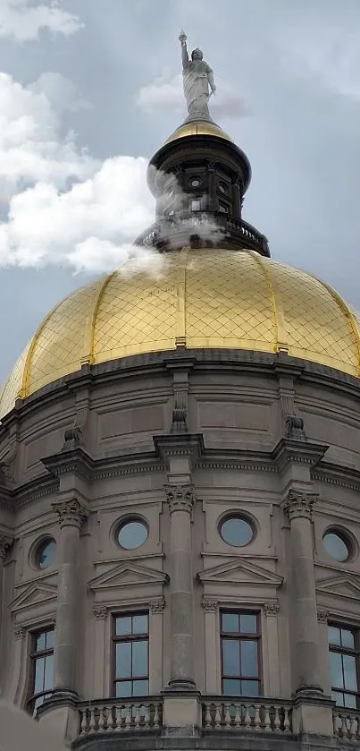 Elegant golden dome with statue and cloudy backdrop.