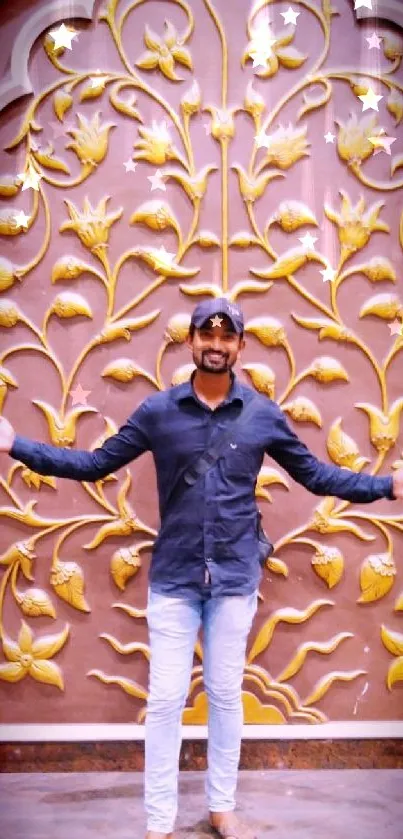 Person in front of a golden floral wall design.