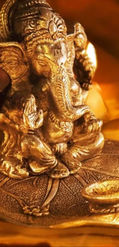 Golden Ganesha statue with an oil lamp and warm lighting.