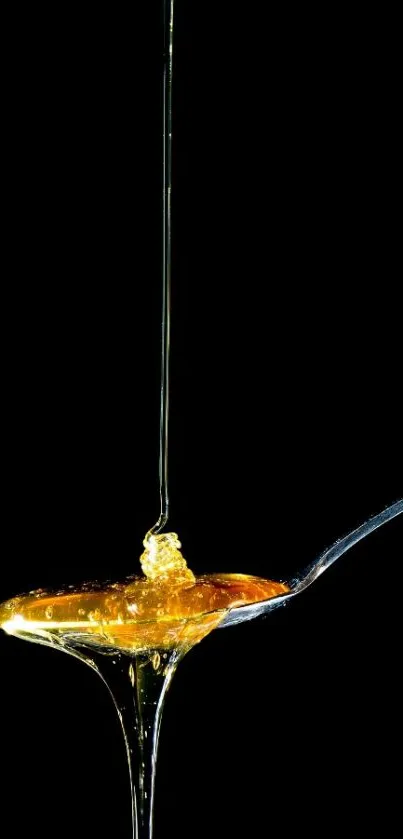 Golden honey flowing onto a spoon with black background.