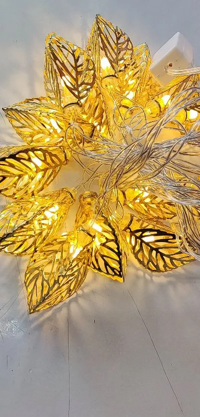 Golden leaf string lights creating a warm, elegant glow on a neutral backdrop.