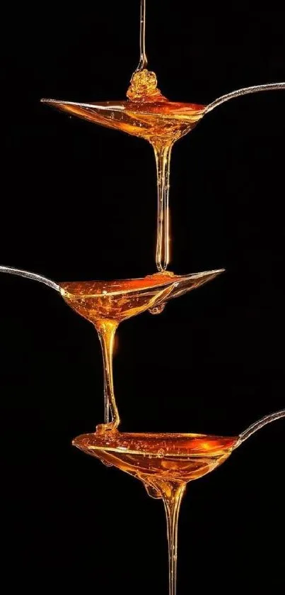 Golden liquid on silver spoons against black backdrop, elegant mobile wallpaper.