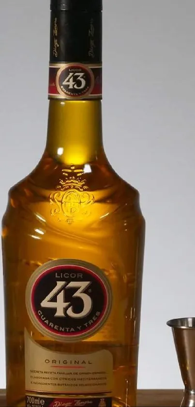 Golden liquor bottle with jigger on wooden surface.