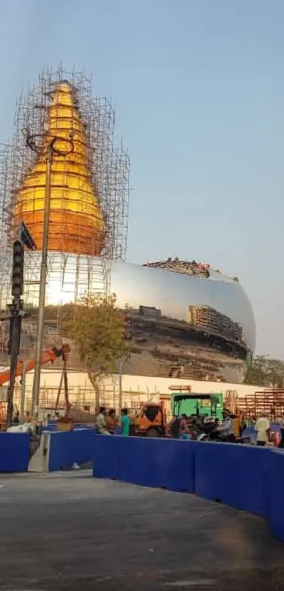 Golden monument under construction with blue sky.