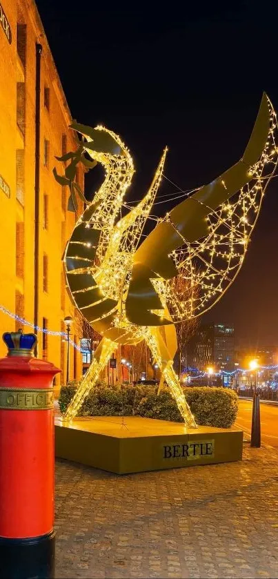 Illuminated golden sculpture at night with urban backdrop and street lights.