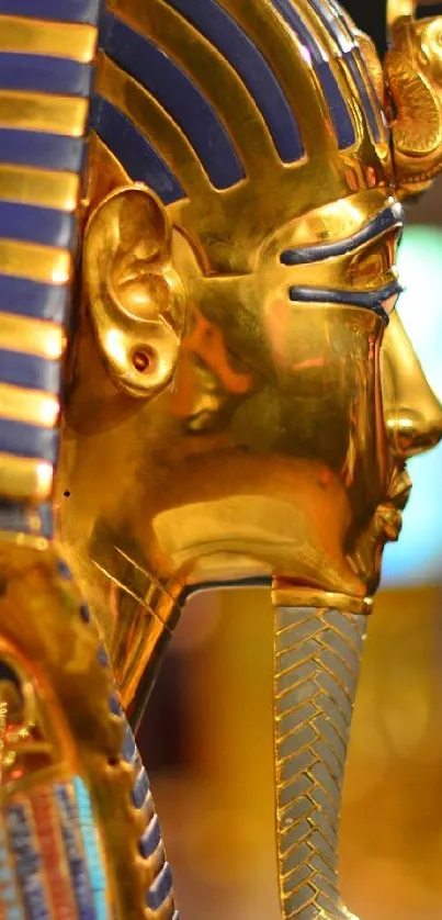 Golden Egyptian pharaoh mask with ancient, intricate designs in bokeh background.