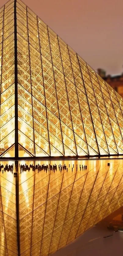 Golden glass pyramid reflecting water at night outside the Louvre.