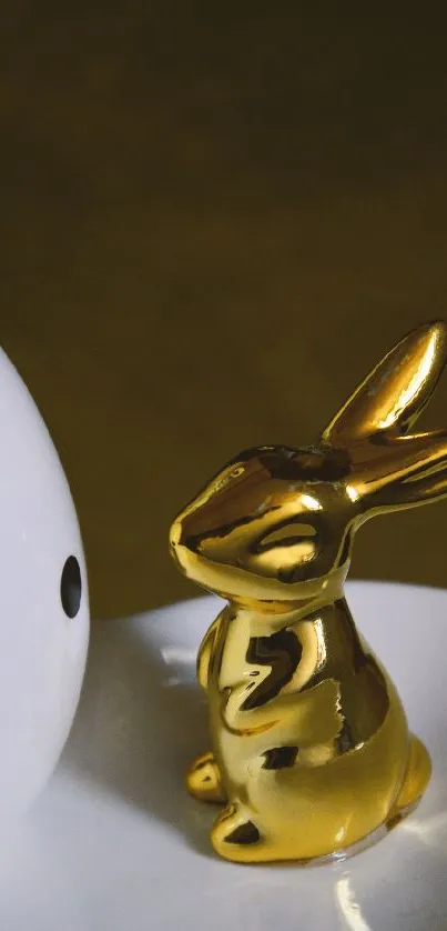 Golden rabbit statue beside white polka dotted egg on a plate.