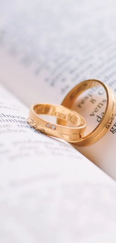 Golden rings resting on open book pages for a romantic mobile wallpaper.