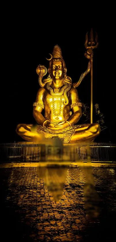 Golden statue of Lord Shiva with reflection on dark background.