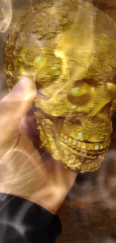 Hand holding a golden skull against a dark background.