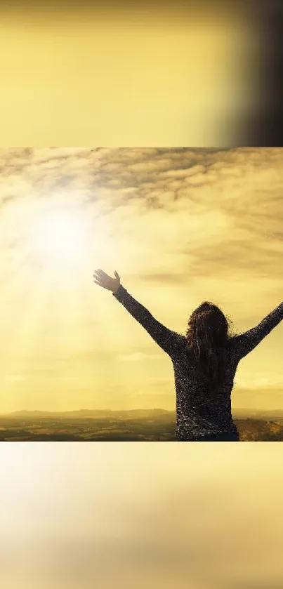 Silhouette with arms raised under a golden sky at sunset.