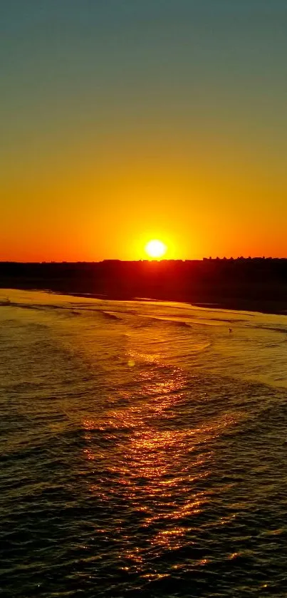 Golden sunset over tranquil beach with waves.