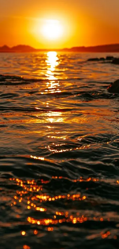 Golden sunset over ocean with shimmering water reflections.