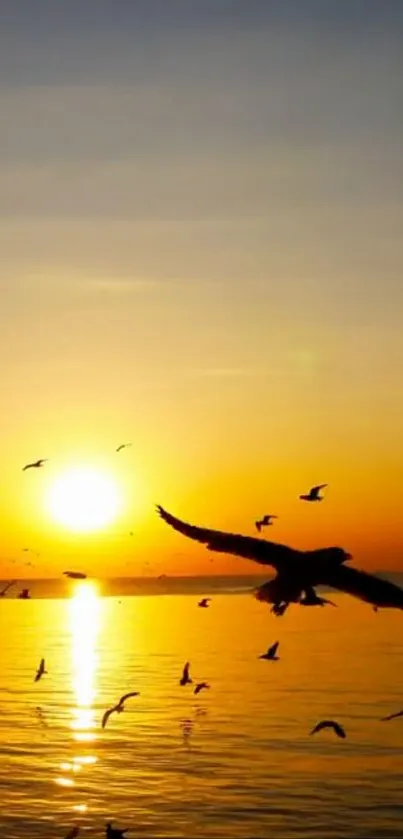 A golden sunset over the ocean with birds flying.