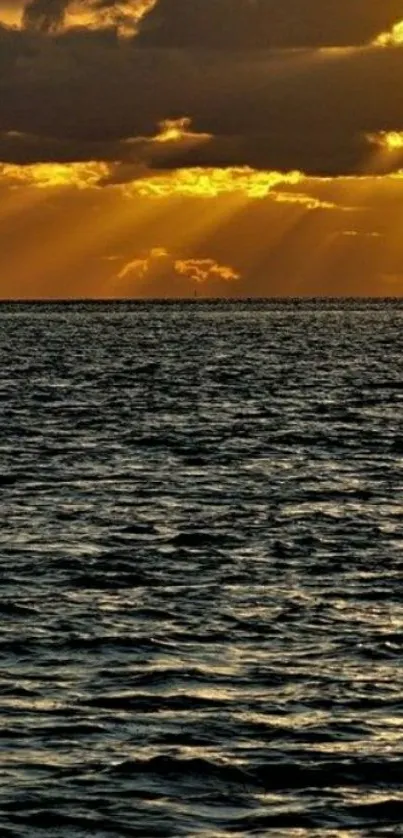 Golden sunset over ocean with shimmering water waves and cloudy sky.