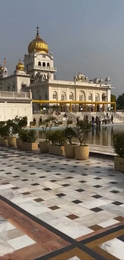 Golden Temple with marble pathway and plants in view.