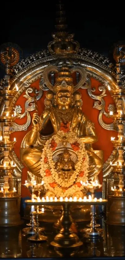 Golden deity statue lit with numerous candles creating a divine atmosphere.