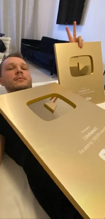 Man with golden YouTube award on bed.