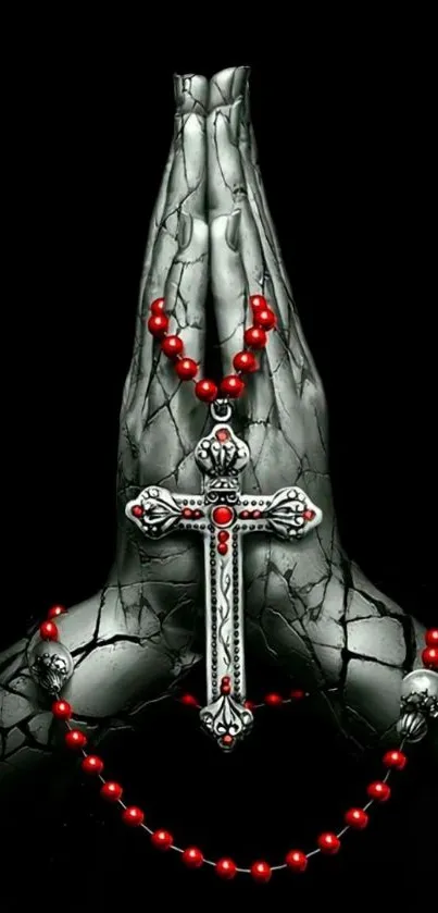 Gothic cross with red rosary on praying hands sculpture.