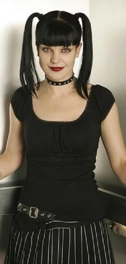 Person with black pigtails in gothic fashion, dark outfit, and studs.